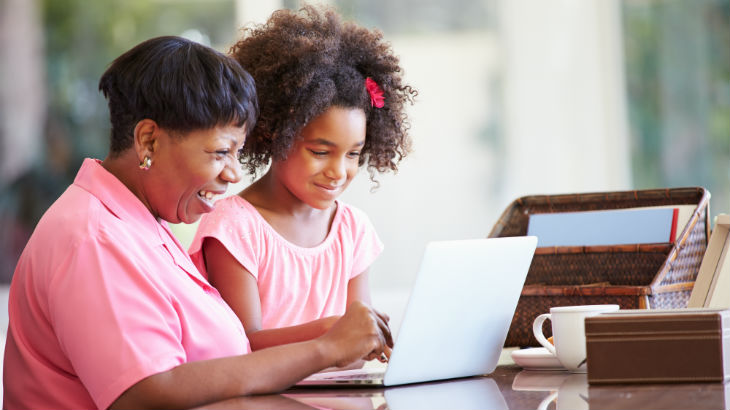 An older woman working on a laptop alongside her daughter